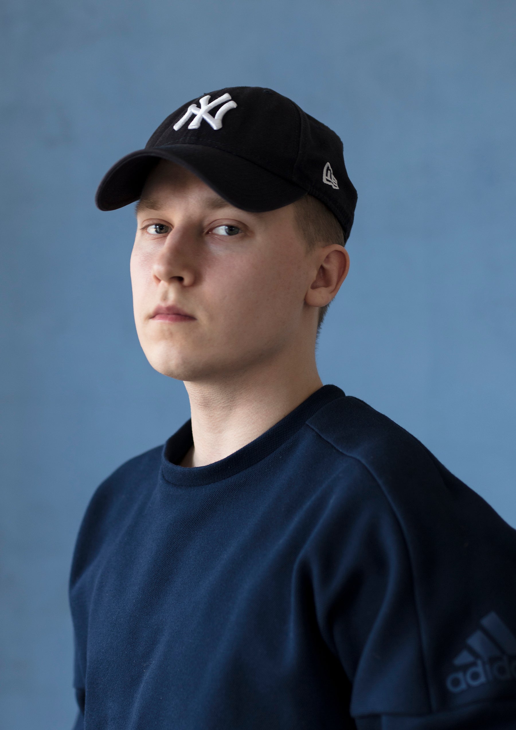 Artor Jesus Inkerön sinitaustainen omakuva, jossa hänellä on yllään sinertävä Adidas college-paita ja New York Yankees -lippis päässään.